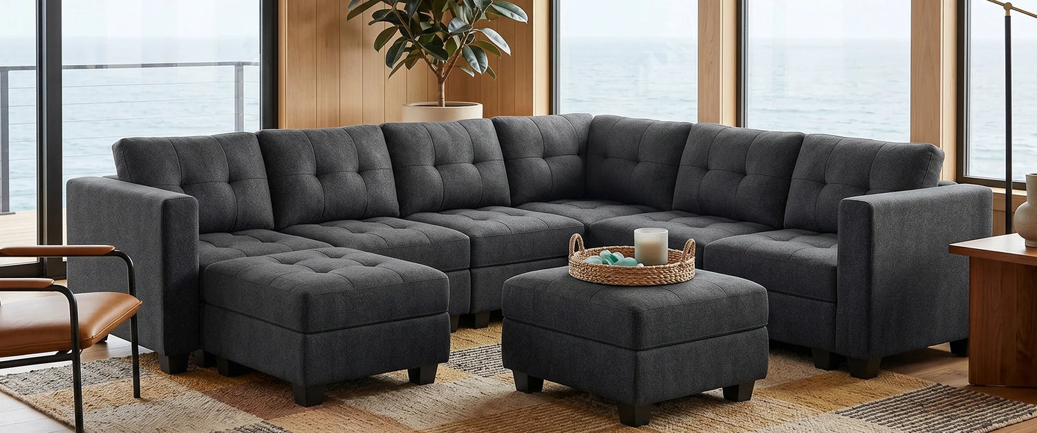 Belffin-Charcoal-grey-modular-sectional-sofa-with-footstools-in-a-modern-living-room-with-large-windows-and-a-sea-view.