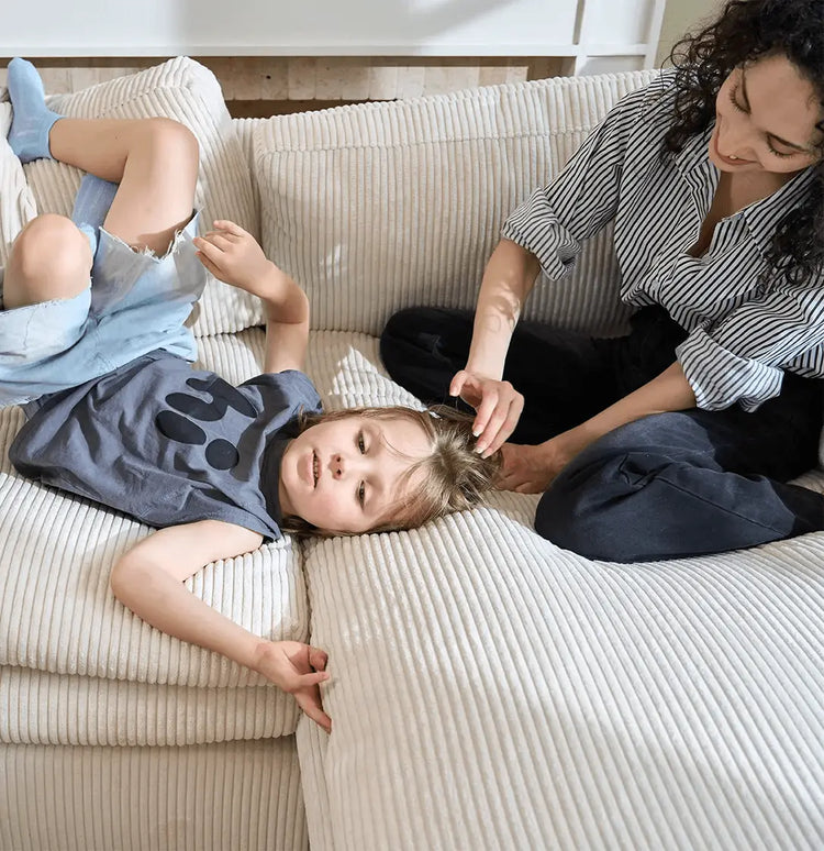 Woman and child lying on a couch, with the woman adjusting the child's hair.